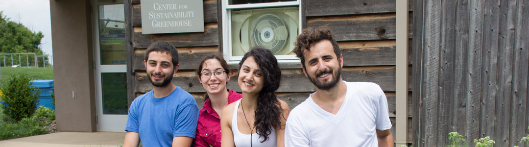 Students sitting at a picnic table in front of the eco-machine.