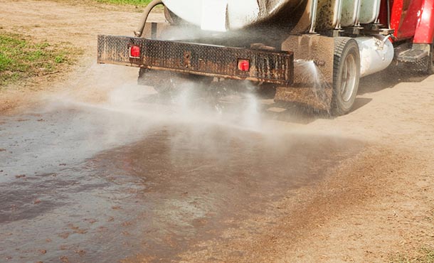 wastewater being spread by truck onto dirt road