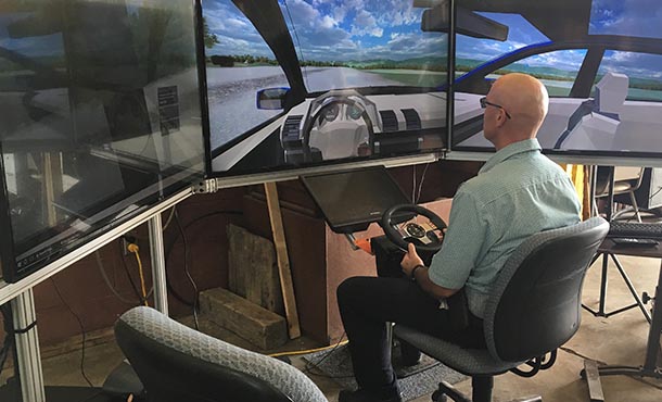 man sitting in driving simulator with two screens in front of him